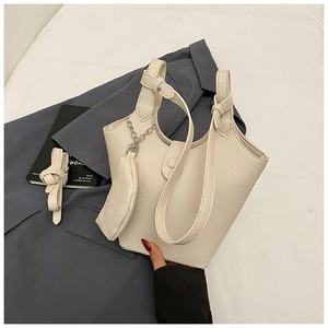 Detail of cream lychee texture leather bucket bag with matching mini pouch on white linen
