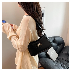 Détail d'un sac sous le bras en cuir noir à texture crocodile avec boucle dorée