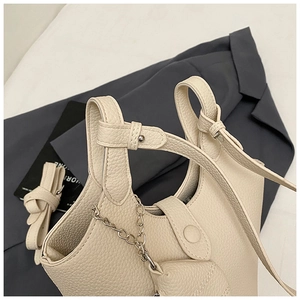 Detail of off-white lychee grain leather bucket bag with silver chain and heart charm