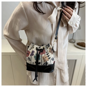 Detail of bohemian bucket bag with vintage floral embroidery and black leather strap