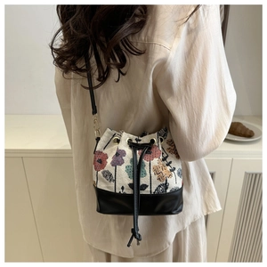 Detailed back view of a floral woven and black leather bucket bag with drawstring closure