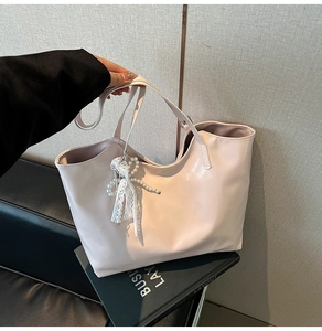 Dettaglio borsa tote rosa in ecopelle con ciondolo a fiocco in pizzo e perle decorative