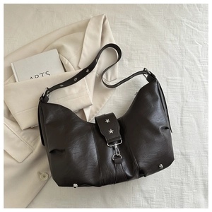Detail of dark brown Hobo bag with silver star rivets and metal buckle on blazer
