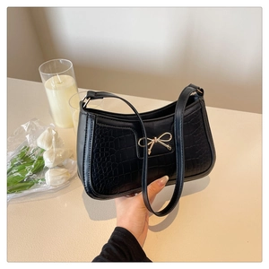 Détail du sac sous l'aisselle en cuir crocodile avec nœud papillon en métal doré