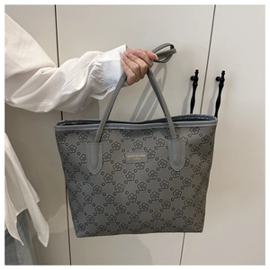 Detailed view of a grey tote bag with floral prints and sturdy shoulder straps.
