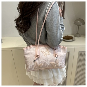 Detail view of pink lace shoulder bag with floral embroidery and 3D butterfly appliques