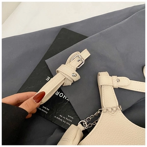 Detail of cream-colored lychee textured leather bucket bag with silver buckle and chain