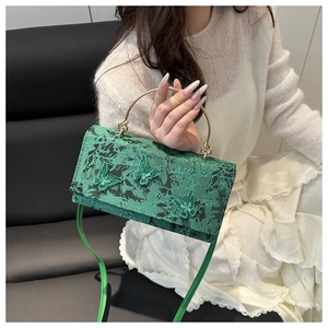 Detail of green lace handbag with 3D butterfly embroidery and gold metal ring handle