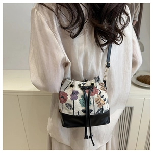 Detailed back view of a woman wearing the vintage floral embroidered drawstring bucket bag