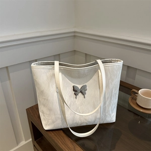Elegant white tote bag with marble texture and silver butterfly on a wooden table