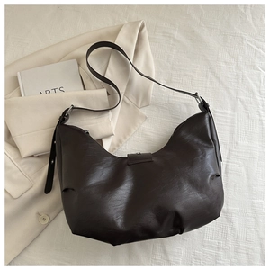 Detail view of dark brown hobo bag with litchi grain texture and adjustable strap