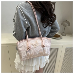 Detail of pink floral lace shoulder bag featuring decorative white 3D butterfly appliques