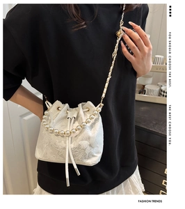 Close-up of white lace bucket bag with 3D butterfly decor and pearl handle chain