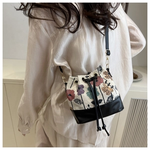 Detailed side view of an ethnic bucket bag with floral knit and leather drawstring