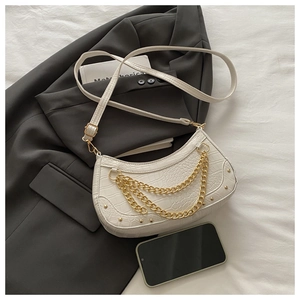 Detail of white crocodile embossed baguette bag with gold chains and stud accents