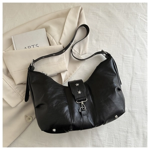 Detail view of black vintage leather tote bag with silver star rivets on the shoulder strap
