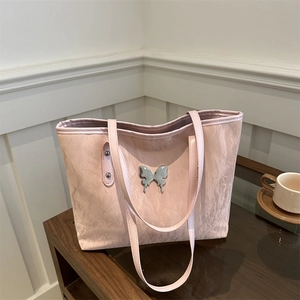 Pink pleated tote bag with silver butterfly logo on wooden table for daily commute