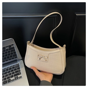 Close-up of cream white faux crocodile leather shoulder bag with metal bow detail