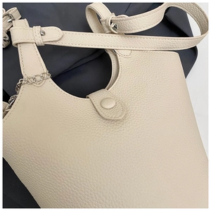 Close-up of cream lychee leather bucket bag with metal chain and magnetic buckle