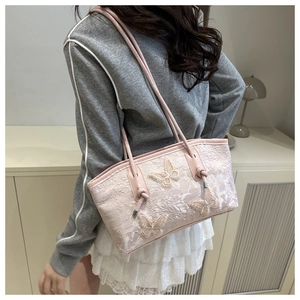 Close-up of pink lace tote bag with 3D butterfly embroidery shown on a model