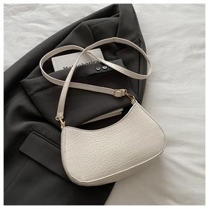 Detail of off-white faux crocodile texture shoulder bag on a black blazer with gold hardware