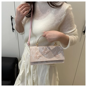 Close-up of 3D butterfly embroidery and metal handle on the pink rectangular crossbody bag