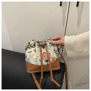 Detail of ethnic bucket bag featuring floral brocade tapestry and brown leather trim