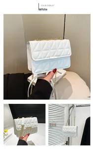 Close-up of white quilted handbag with golden chain strap and triangular stitching pattern