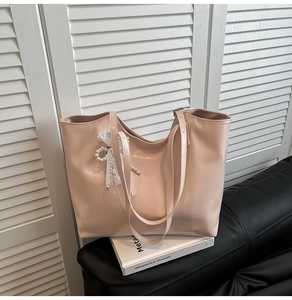 Dettaglio borsa tote in pelle PU rosa chiaro con ciondolo in pizzo bianco e perle