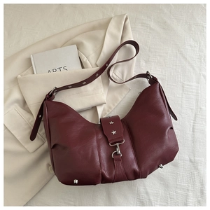 Detail of burgundy lychee leather shoulder bag featuring star studs and buckle closure