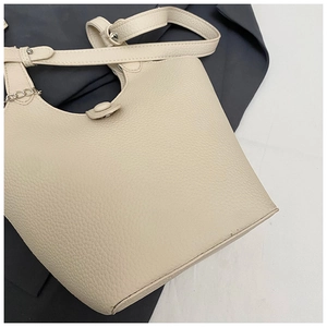 Detail view of cream pebble leather bucket bag with metallic chain strap hardware
