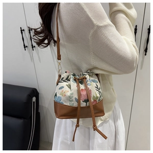 Close-up of floral jacquard bucket bag with brown leather base and drawstring closure