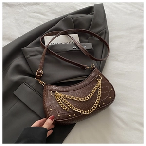 Détail du sac marron foncé embossé croco avec triple chaîne dorée et finitions à rivets