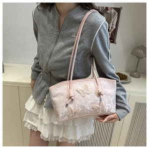 Detail view of pink lace tote bag featuring 3D butterfly appliques and leather handles