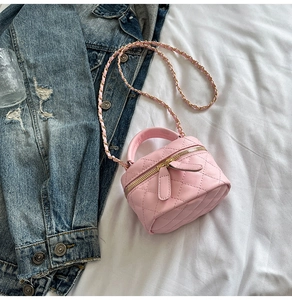 Detail of pink quilted mini crossbody bag with gold chain and leather handle on casual bed scene