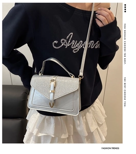 Detail of silver sequined handbag featuring a gold buckle and adjustable shoulder strap