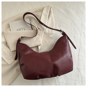 Deep red hobo bag with natural leather texture and adjustable strap on a neutral blazer