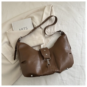 Detail of vintage brown hobo bag featuring silver star studs and adjustable leather strap