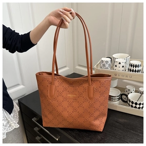 Detail of the elegant brown tote bag featuring a textured floral pattern and handles