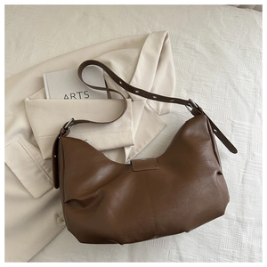 Detail of a brown leather hobo bag with star-shaped metal studs and pleated bottom detail
