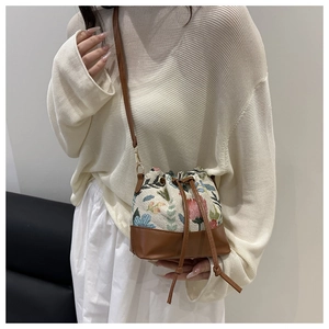 Close-up of ethnic bucket bag featuring floral embroidery and brown leather base details
