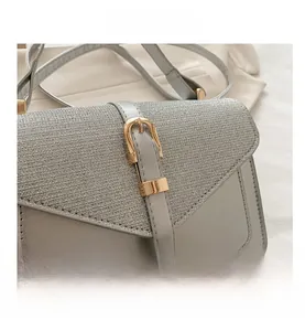 Detail of grey crossbody bag featuring mixed textures and a gold horsebit buckle