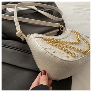 Detail of white crocodile texture half-moon bag with triple gold chain decor