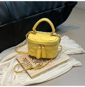 Detail view of yellow quilted mini vanity bag with leather-interwoven chain strap and handle