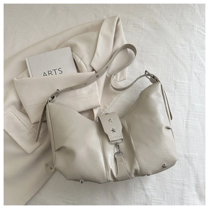 Detail of beige half-moon shoulder bag with silver star studs on soft leather texture