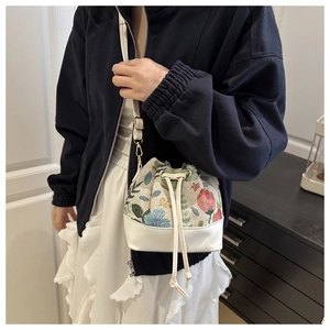 Close-up of floral jacquard bucket bag with white leather trim and gold hook