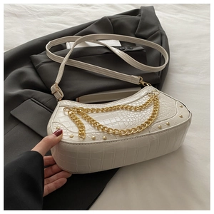 Detail of white crocodile pattern bag with golden chain and studs on grey suit