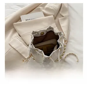 Detail of white drawstring bucket bag interior with pearl handle and chain strap