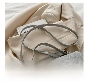 Close-up of adjustable fine shoulder strap with gold-tone hardware on grey handbag