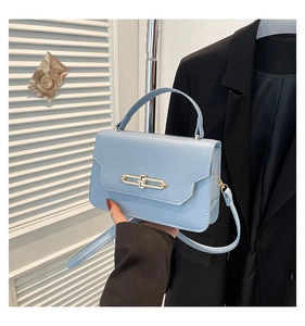 Close-up of light blue leather square bag with gold H-shaped hardware and top handle